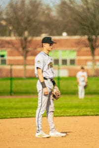 Player in gray baseball uniform stands on the field, ready for play during a sunny game day.