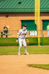 Baseball player in gray uniform poised at second base, ready for action on a sunny day at the baseball field.