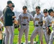 Alt text: Baseball team huddled on the pitcher's mound, discussing strategy during a sunny game day.