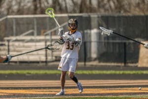 Lacrosse player in action on the field, showcasing skills with a bright green stick and focused expression.