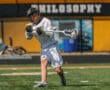 Lacrosse player in action, executing a pass on the field during a sunny day, showcasing athletic skill and teamwork.