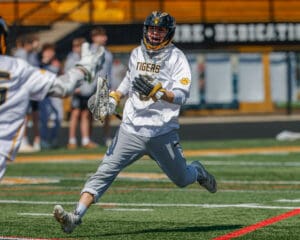 High school lacrosse player in action, sprinting on the field, ready to make a play during a sunny spring practice.