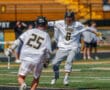 Two lacrosse players celebrate a goal on the field, showcasing teamwork and excitement in a vibrant sports setting.