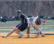 Two lacrosse players compete for the ball on a vibrant turf field, showcasing athletic intensity and teamwork.