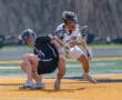 Two lacrosse players compete for the ball on a vibrant field during an intense match, showcasing athleticism and sportsmanship.