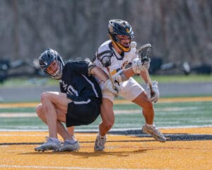 Two lacrosse players compete for the ball on a vibrant field during an intense match, showcasing athleticism and sportsmanship.