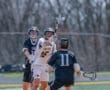 Two lacrosse players compete for possession of the ball, showcasing athleticism on a sunny field.
