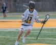 Lacrosse player in a Tigers jersey #13 dribbles the ball on the field during a game, showcasing athleticism and focus.