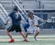 Two high school lacrosse players face off on the field, showcasing athleticism and competitive spirit during a game.