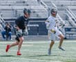 Two young lacrosse players compete on the field, showcasing athleticism during an outdoor game.