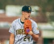 Young baseball player in gray Tigers uniform, preparing to pitch, focused on the game with glove and ball in hand.
