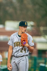 Young baseball player in gray Tigers uniform, preparing to pitch, focused on the game with glove and ball in hand.