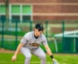 A young baseball player in a Tigers uniform prepares to field a ball on the infield during a game.