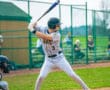 A baseball player swings a bat during a game, showcasing action and athleticism on a sunny field.