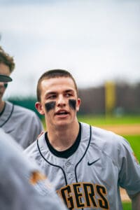 Baseball player in gray jersey speaks passionately to teammates, showcasing determination and team spirit on the field.