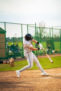 A young baseball player swings his bat, making contact with the ball during a sunny game on the diamond.