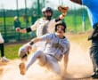 Baseball player slides into home base while umpire calls the play, capturing the excitement of the game.