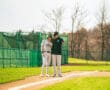 Coaches discussing strategies with a player on a baseball field, showcasing teamwork and training in action.