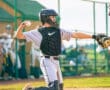 A young baseball catcher prepares to throw a ball during a game, showcasing athleticism and focus on the field.