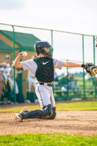 A young baseball catcher prepares to throw a ball during a game, showcasing athleticism and focus on the field.