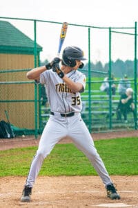 Baseball player in gray uniform prepares to bat, showcasing focus and athleticism on the field.