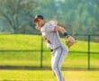 A young baseball player in a white uniform pitches on a sunny field, showcasing athleticism and focus.