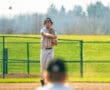 Baseball player makes a throw from shortstop position during a sunny game, highlighting athleticism and teamwork.