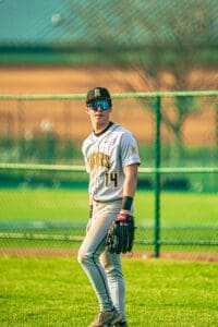Young baseball player in Tigers uniform stands on the field, ready in the outfield with focus and determination.