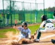 Baseball player slides into home plate while catcher prepares to tag him during an exciting game on a sunny day.