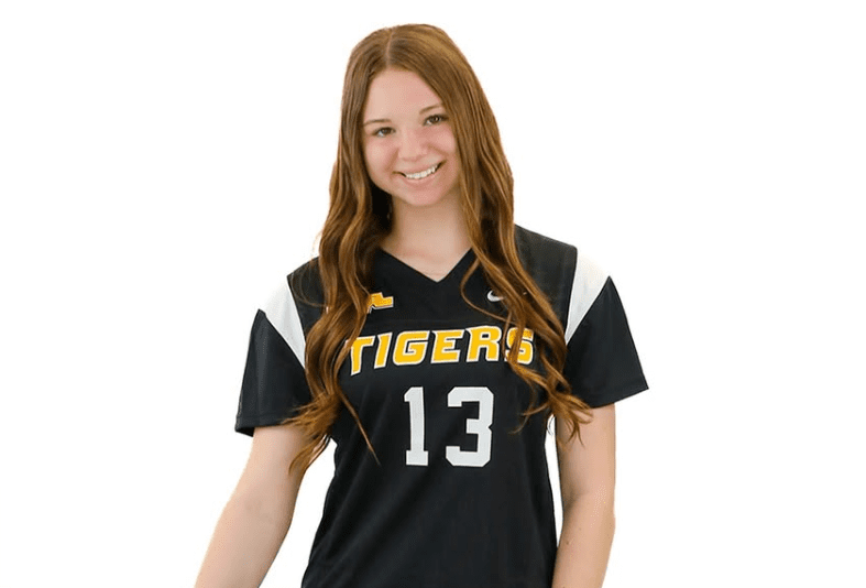Smiling young athlete in a black volleyball jersey with Tigers and number 13, posing confidently against a white background.
