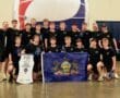 Boys' volleyball team from North Allegheny, PA, celebrating with flags and a banner at a national tournament.