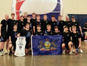 Boys' volleyball team from North Allegheny, PA, celebrating with flags and a banner at a national tournament.