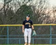 Young baseball player in a Tigers uniform stands on the field, holding a glove and looking focused during practice.