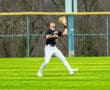 Baseball player preparing to catch a fly ball on a sunny day in the outfield, showcasing athleticism and focus.