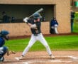 A young baseball player prepares to bat as the catcher readies for a pitch in a competitive game setting.