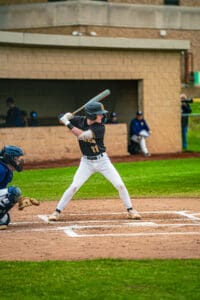 A young baseball player prepares to bat as the catcher readies for a pitch in a competitive game setting.