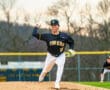 High school baseball pitcher wearing a Tigers jersey winds up to throw a pitch on the mound during a game.