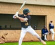 High school baseball player in a batting stance, preparing to hit during a game on a sunny day.