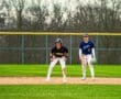 Two baseball players on the field: one in black and gold, the other in blue and white, preparing for the next play.