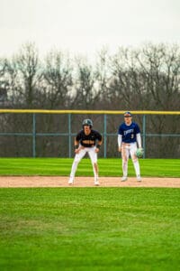 Two baseball players on the field: one in black and gold, the other in blue and white, preparing for the next play.