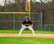 Baseball player in a crouched position on the field, focused and ready for the next play in a sunny afternoon game.