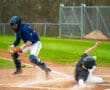 A baseball catcher prepares to tag out a sliding player at home plate during an action-packed game.