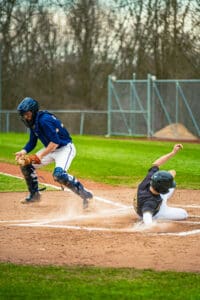 A baseball catcher prepares to tag out a sliding player at home plate during an action-packed game.