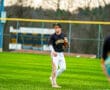 A young baseball player in a Tigers uniform stands on the field, ready for action during a game.