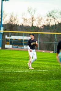 A young baseball player in a Tigers uniform stands on the field, ready for action during a game.