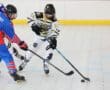 Youth ice hockey players compete on a rink, focusing on puck control and teamwork during an intense match.