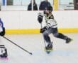 A young roller hockey player skates swiftly, stick in hand, during a competitive game on the rink.
