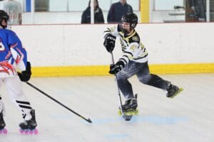 A young roller hockey player skates swiftly, stick in hand, during a competitive game on the rink.