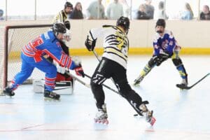 Youth roller hockey players compete in a fast-paced game, showcasing skills in a brightly lit rink.