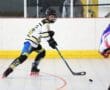 Youth roller hockey player in action, skillfully skating and controlling the puck on a rink.